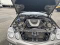 A 2007 Mercedes-Benz E-Class with its hood raised, showcasing the engine compartment and various mechanical components visible inside