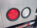 Two circular vehicle lights mounted on a silver panel one red and one white each with a textured surface