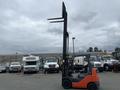 A 2011 Toyota Forklift with a black mast and orange body is positioned with its forks raised above the cabin