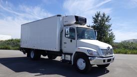 A 2009 Hino 268 truck with a white cargo box and refrigeration unit on top facing forward