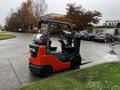 A 2017 Toyota 8FCGCU25 forklift with an orange and black color scheme parked with its forks lowered and gas canister mounted on the side