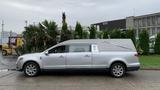 A silver 2013 Lincoln MKT hearse with a long body and a curved roof design parked on a street