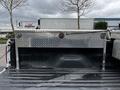 A 2011 Ford F-250 SD truck bed with a diamond plate toolbox featuring two round locks on the front