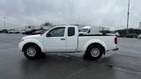 A white 2016 Nissan Frontier pickup truck with a two-door cab and a black bed liner is parked on a paved surface