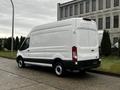 A white 2021 Ford Transit van with a high roof and rear cargo door parked on a concrete surface