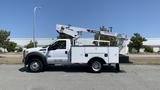 A white 2011 Ford F-450 Super Duty truck with a bucket lift mounted on the rear and tool compartments on the sides