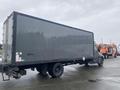 A 2018 Hino 308 box truck with a gray exterior parked at an angle showcasing its side and rear without any visible branding or markings