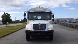 A 2015 International PC105 bus facing directly forward with its headlights on and a white exterior