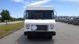 A white 2011 Ford Econoline van with a flat front and a blank license plate holder positioned in a parking lot