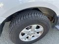 Close-up of a silver 2013 Ford Expedition's wheel featuring a five-spoke alloy rim and a detailed tire tread pattern