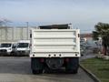 A white 2015 International DuraStar 4300 truck viewed from the rear with a flatbed and tarpaulin on top