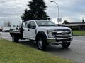 A 2021 Ford F-550 flatbed truck in white with a dual rear wheel configuration parked on a street