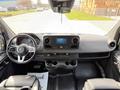 Interior view of a 2019 Mercedes-Benz Sprinter featuring a steering wheel dashboard and center console with controls and cup holders