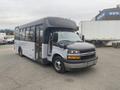 A 2017 Chevrolet Express shuttle bus with a black front and white body featuring large windows and a partially open door