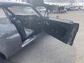 A 1966 Ford Mustang with an open driver-side door revealing a black interior and dashboard