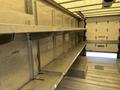 Interior of a 2012 Ford Econoline van featuring metal shelving along the sides and a flat floor surface