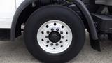 A large black tire mounted on a silver rim with multiple lug nut holes, part of a 2007 Autocar WXLL truck