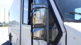 A 2006 Ford Econoline with a silver side mirror reflecting light and a white exterior showing signs of wear