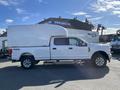 A white 2019 Ford F-350 SD pickup truck with a large cargo cap on the bed and four-wheel drive features
