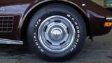 A side view of a 1971 Chevrolet Corvette Stingray showcasing its wheel and tire with white lettering and a silver rim