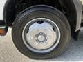 Close-up of a silver wheel with six lug nuts mounted on a black tire featuring a tread pattern designed for road grip