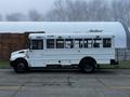 A white 2016 International 4200 bus with a flat roof and large windows is parked with its side facing the viewer