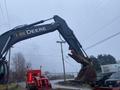 A 2014 John Deere 350G excavator with an extended arm and bucket raised up showcasing its heavy machinery design