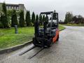 A 2017 Toyota 8FCGCU25 forklift with a black and orange body and two long forks in the front positioned on a concrete surface