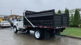 A white 2021 International CV515 truck with a black dump bed is parked with its tailgate slightly lowered