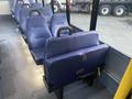 Interior seats of a 2017 Chevrolet Express bus arranged in a row with blue upholstery and sturdy armrests