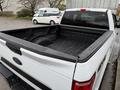 A white 2018 Ford F-150 pickup truck with an open bed showcasing the truck's cargo area and tailgate