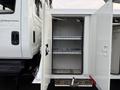 An open truck refrigerated compartment with two metal shelves and a white interior