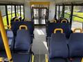 Interior of a 2015 Chevrolet Express with blue seats yellow handles and an aisle leading to the front and rear doors