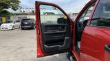 A red 2013 RAM 2500 with the driver's door open, showing the interior door panel and controls