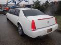 A white 2008 Cadillac Limousine with tinted windows and chrome wheels is parked with its rear view visible