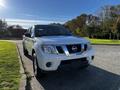 A white 2015 Nissan Frontier parked with a chrome grille and black accents in the front