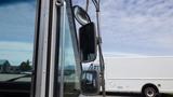 A 2011 Ford Econoline with large side mirrors reflecting light and a partial view of the window glass