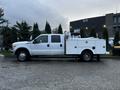 A white 2014 Ford F-350 SD pickup truck with a utility bed and tool compartments on the side