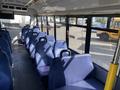 A 2017 Chevrolet Express bus interior featuring rows of blue upholstered seats with a wide aisle running down the center