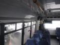 Interior view of a 2016 Chevrolet Express bus showing rows of blue seats and large windows with rain streaks