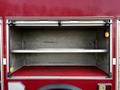 A red 1994 Freightliner FL80 fire truck compartment with two metal shelves illuminated by lights on either side