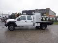 A 2009 Ford F-450 SD white pickup truck with a flatbed and utility box attached to the back