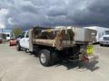 A 2010 Ford F-550 pickup truck with a flatbed and a mounted salt spreader on the back