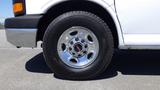 A close-up of a silver wheel with chrome detailing on a 2012 GMC Savana showcasing the tire tread pattern and logo