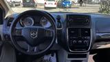 The interior of a 2016 Dodge Grand Caravan featuring a steering wheel with controls a dashboard with gauges and a central console with multimedia and climate controls