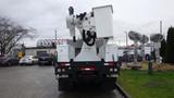 A white 2005 International 4300 utility truck with a raised bucket and a boom arm is parked, showing its rear and equipment attachment points