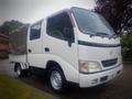 A white 2003 Toyota Toyoace truck with a covered cargo area and large front windows parked at an angle