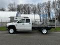 A white 2008 Dodge Ram 5500 flatbed truck with a dual cab and no cargo, showing a side view of the vehicle