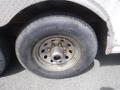 A close-up of a tire mounted on a wheel showing signs of wear with visible rust and dirt on the surface