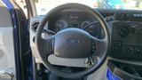 Steering wheel of a 2013 Ford Econoline with the Ford logo and various dashboard controls visible behind it